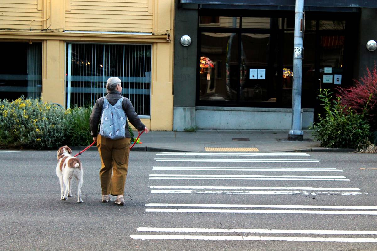 A visually impaired woman hugging her guide dog in front of a bus stop